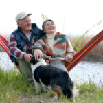 Retired couple sitting on hammock overlooking a stream